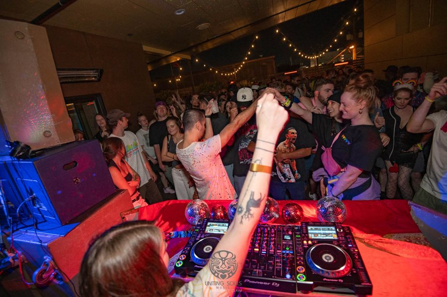 Packed dance floor seen from behind the decks