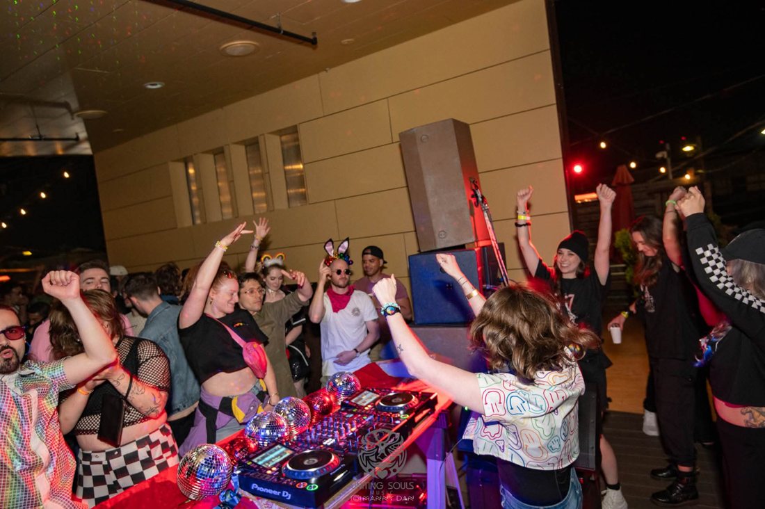 Crowd dancing with arms in the air beside the booth