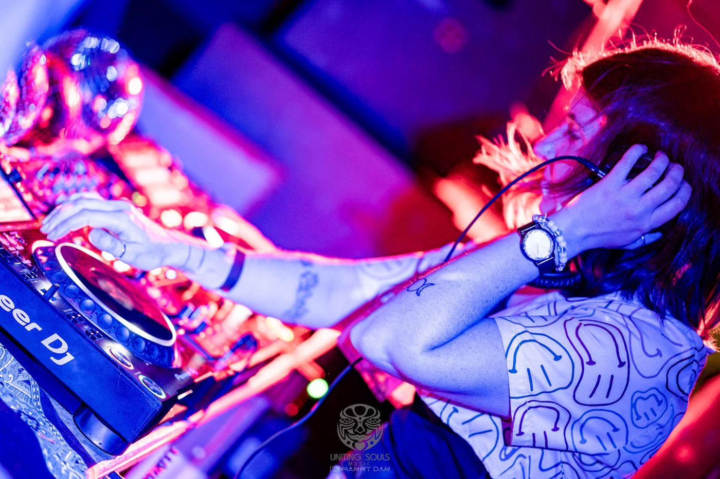 Close-up of AshWave's hands on the decks under blue and magenta light