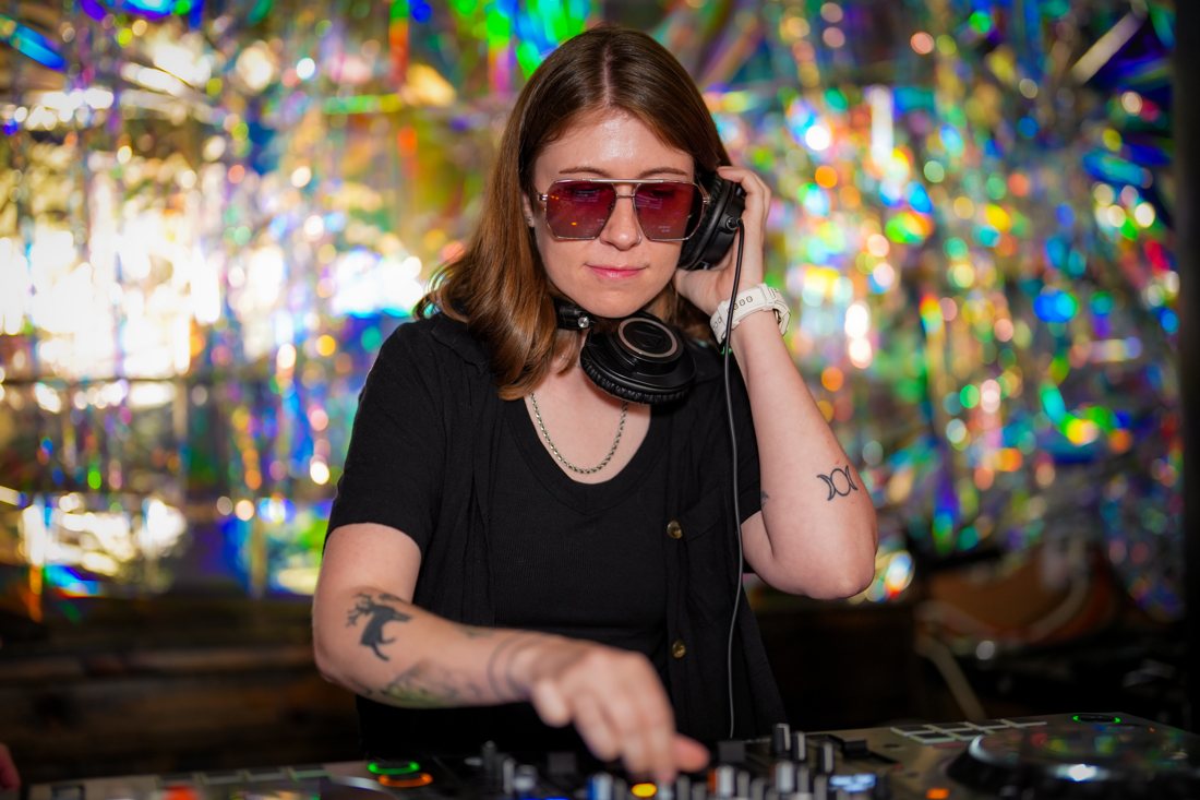 AshWave in red sunglasses at the decks in front of a holographic backdrop